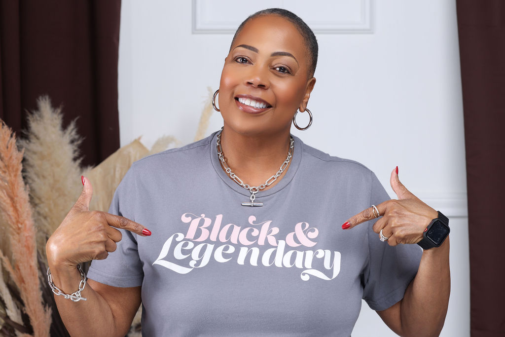 Mary Geter, founder of Fifty and Unfiltered, pointing at her Black and Legendary shirt